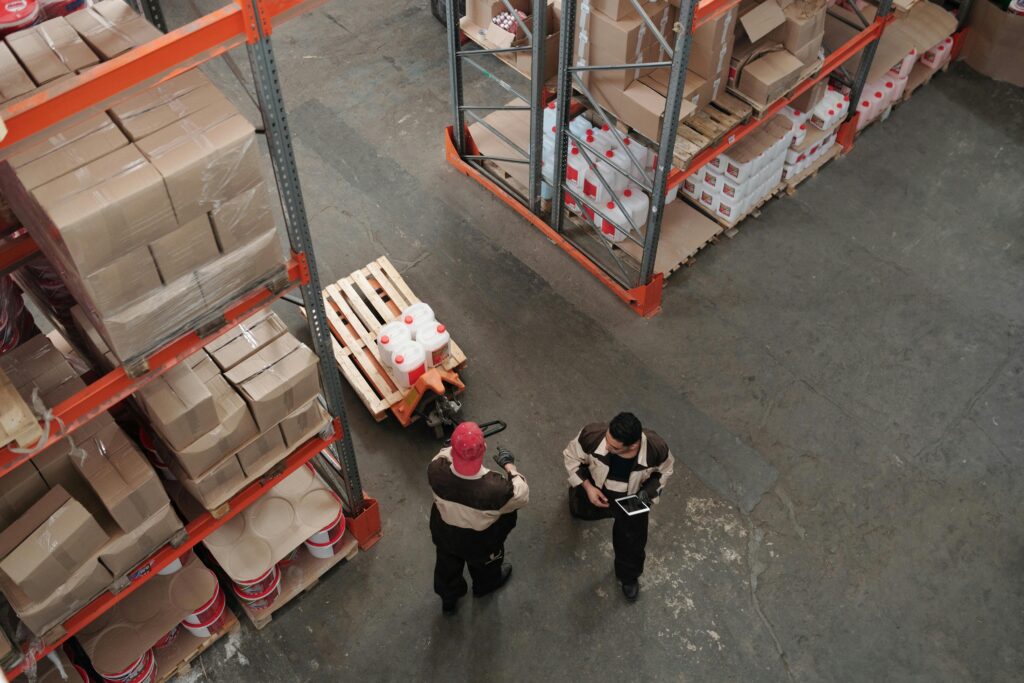High angle view of warehouse workers organizing inventory with pallets and shelves.